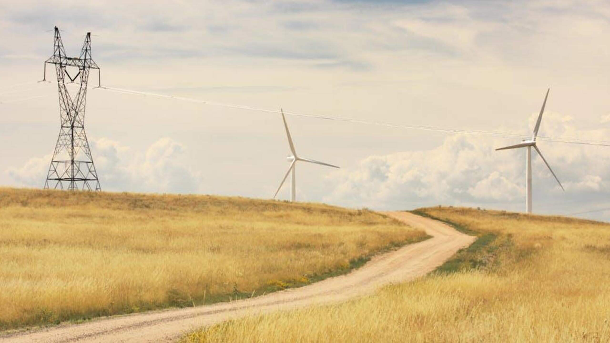 Transmission tower and wind turbines above a prairie road